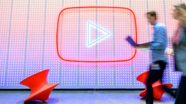 Pessoas caminham em frente ao logotipo do YouTube na sede da empresa em San Bruno, na Califórnia (EUA) Pessoas caminham em frente ao logotipo do YouTube na sede da empresa em San Bruno, na Califórnia (EUA)